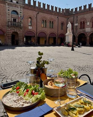 Tavolo del CORE con piatti e bicchieri affacciato sui portici in cotto di Piazza Guercino.